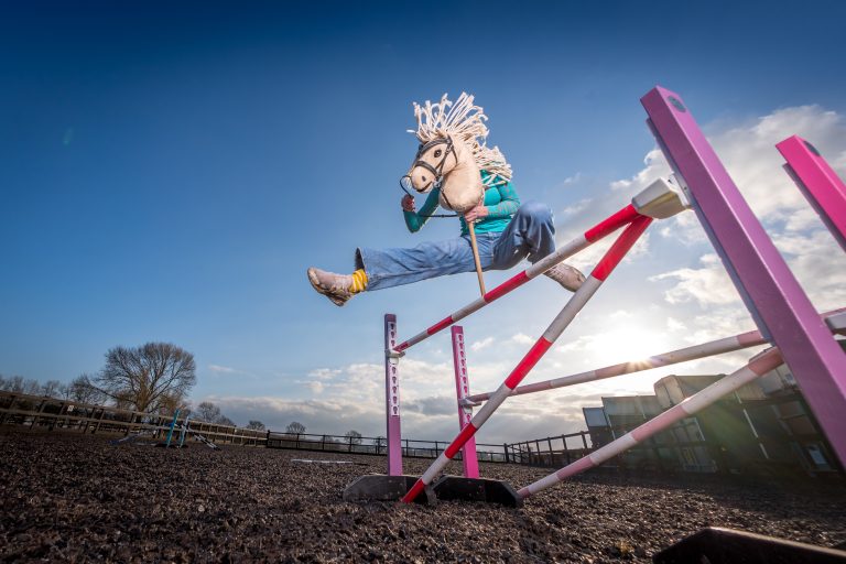 Child jumping over hobby horse jump