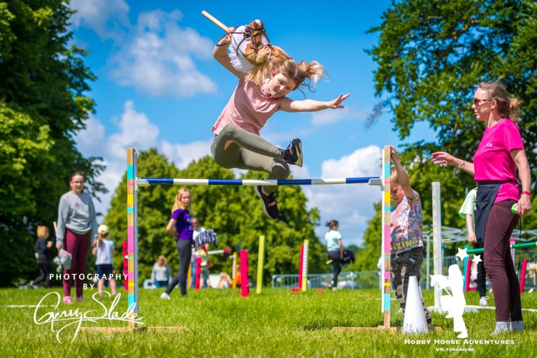 Child jumping over hobby horse jump