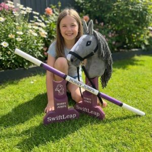Girl with hobby horse sitting by the 30cm jump